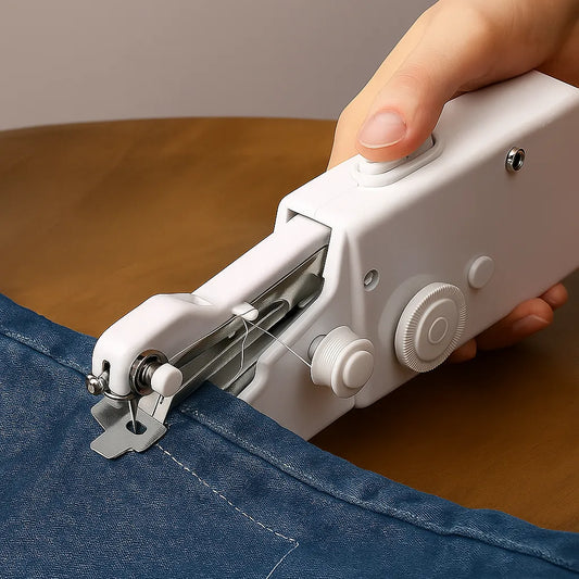Handheld sewing machine stitching blue fabric on a wooden surface